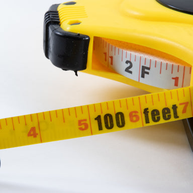 Open tape measure with white tape, a yellow plastic open-style case and geared winding handle
