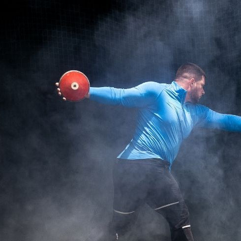 man with red discus in a throwing cage