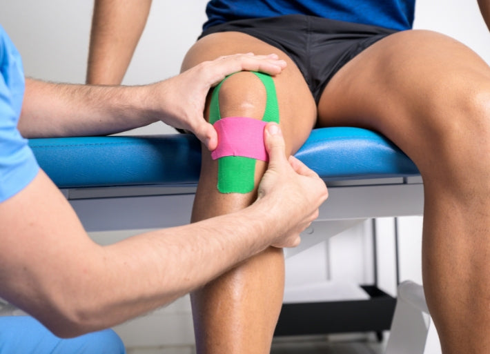 Athlete having kinesiology tape applied to knee