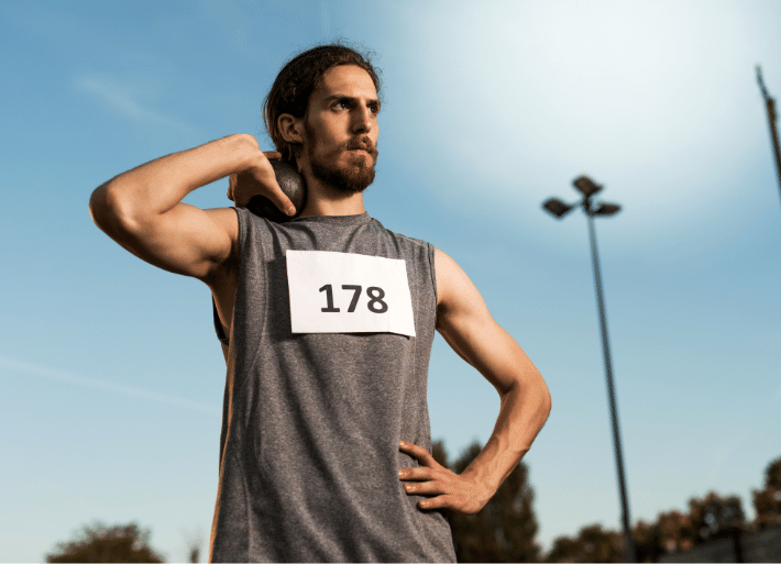 Athlete standing holding a shot put to neck