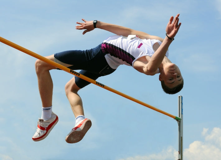 High Jump Athlete clearing a high jump cross bar against the sky