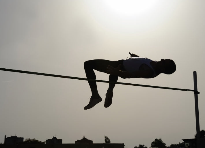 High Jump athlete clearing the bar against a sunset