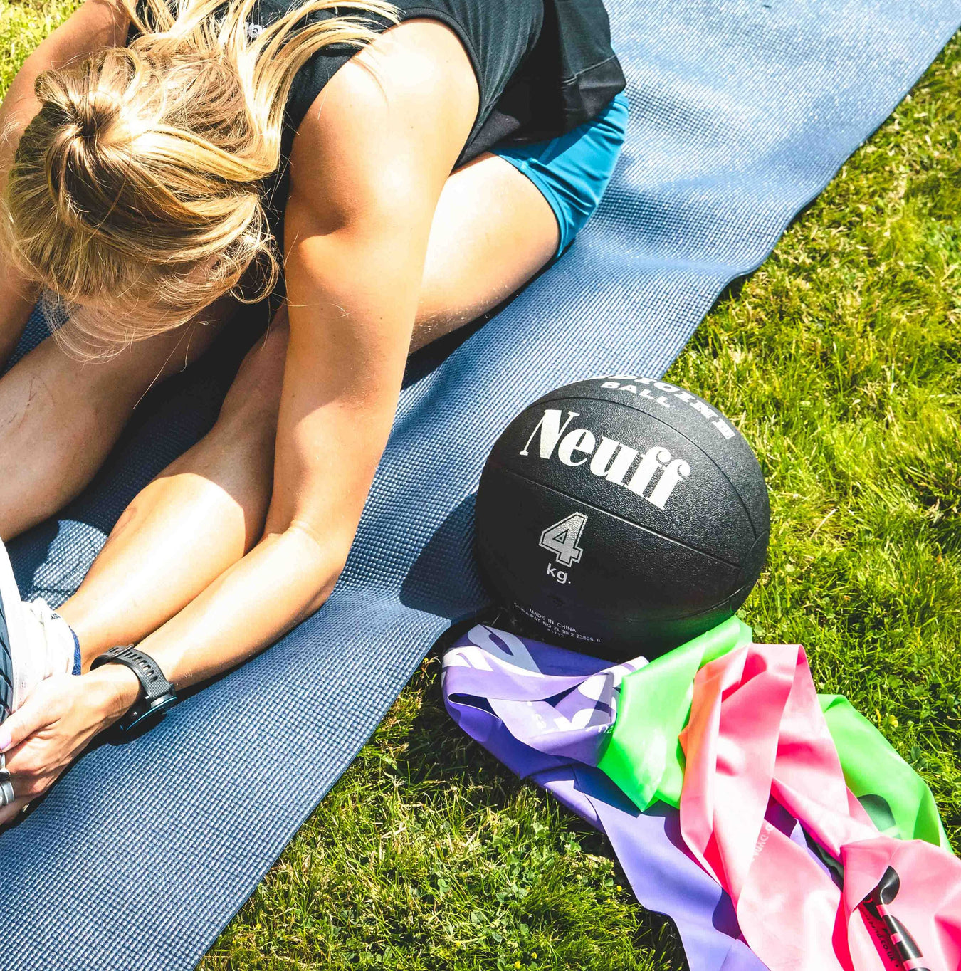 Athlete stretching on a mat with a 'Neuff' medicine ball and Dynaband elastics