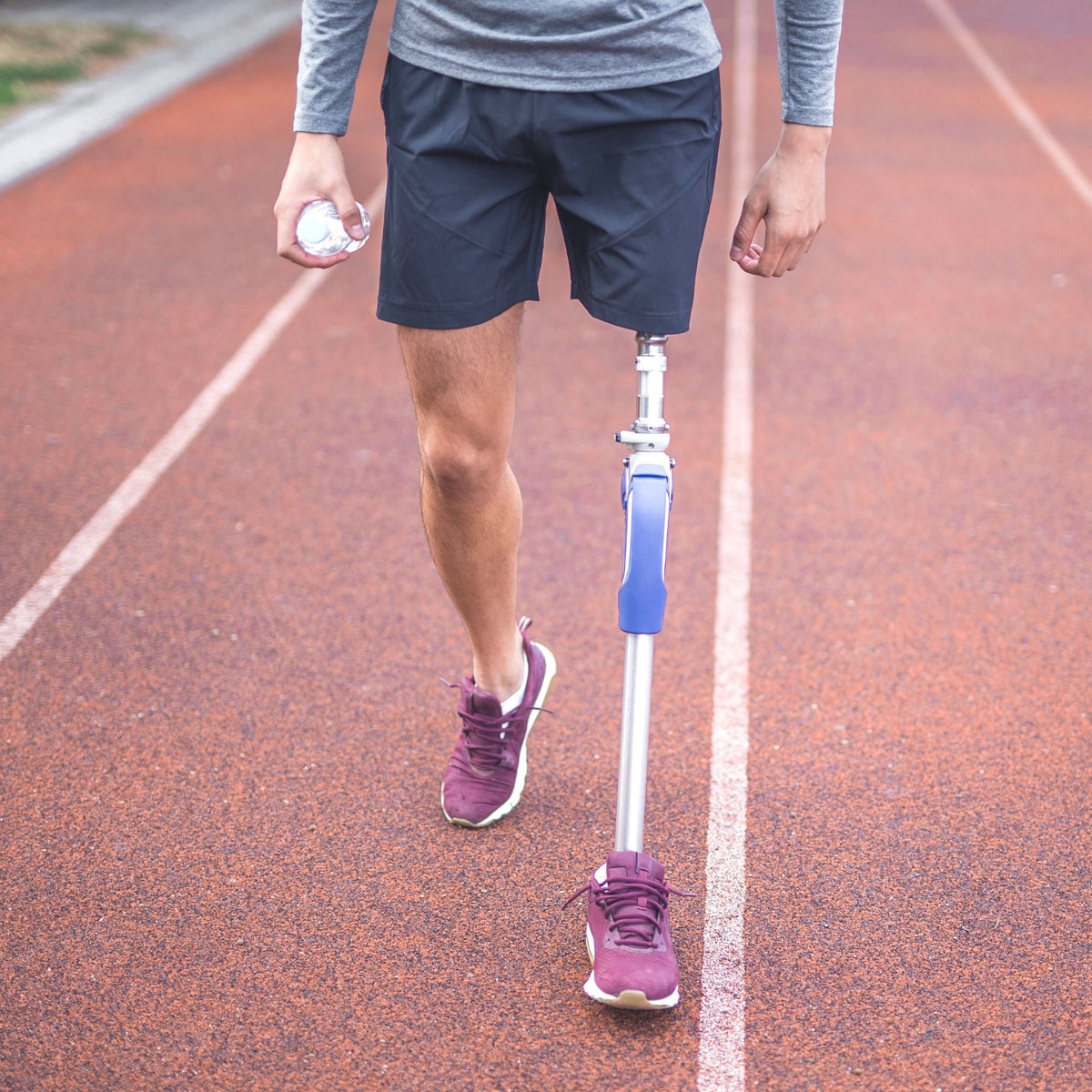 Para athlete with a prosthetic leg walking on an athletics track