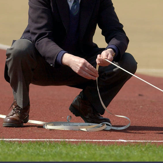 Athletics Official in dark uniform, measuring a distance
