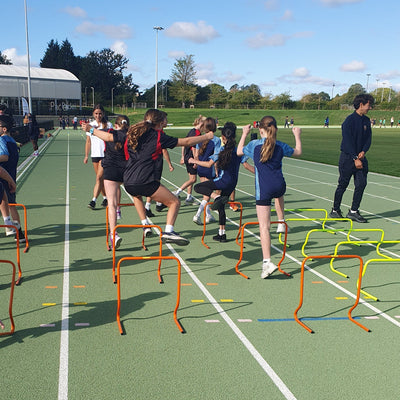School children running over hurdles