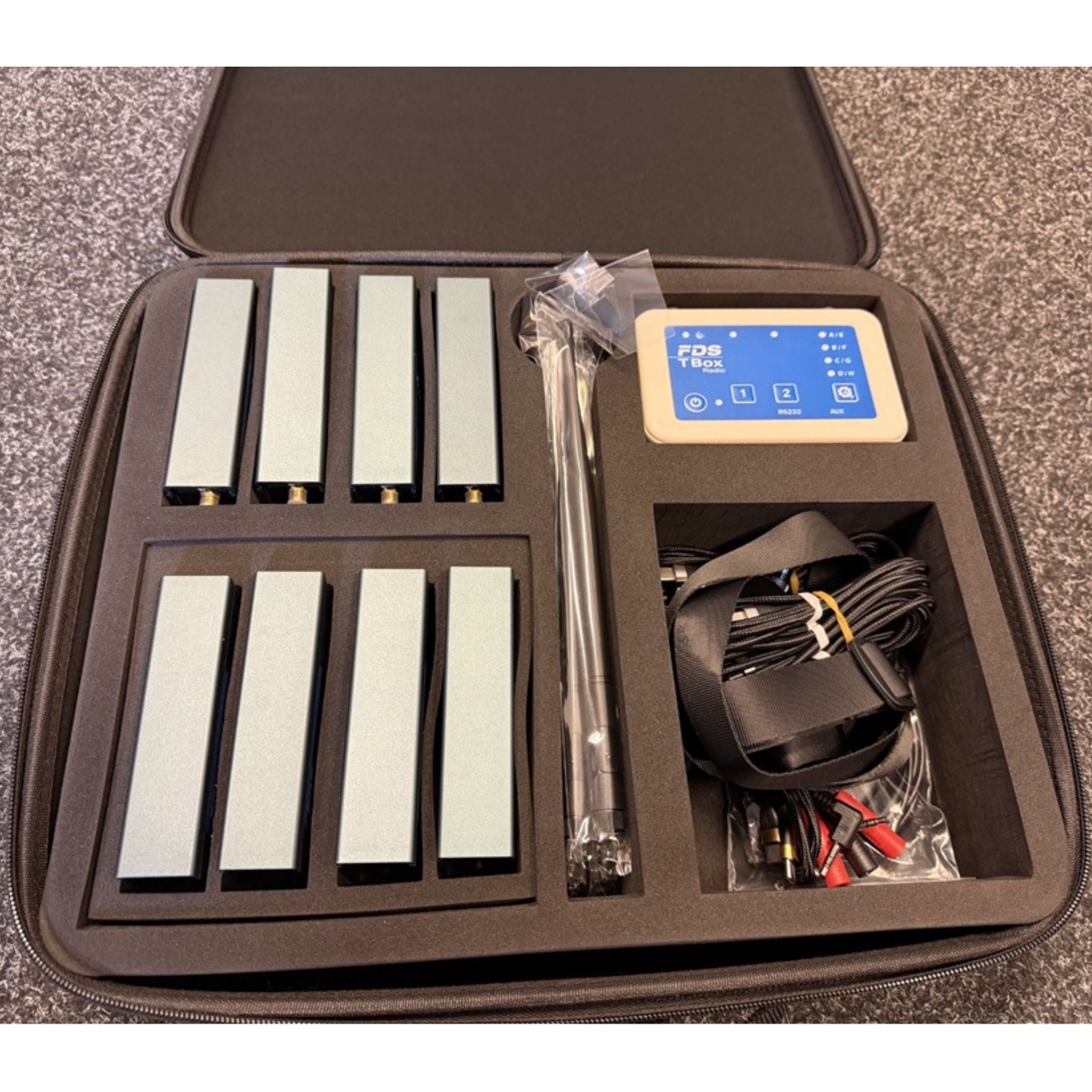 Set of photocells, charging cables and timing device a case on a gray surface