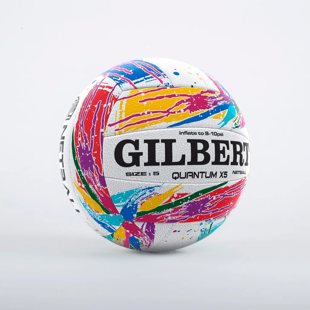 A white netball with a vibrant multicolor paint-splatter pattern and the brand name 'GILBERT' printed in bold black letters on the front, set against a white background.