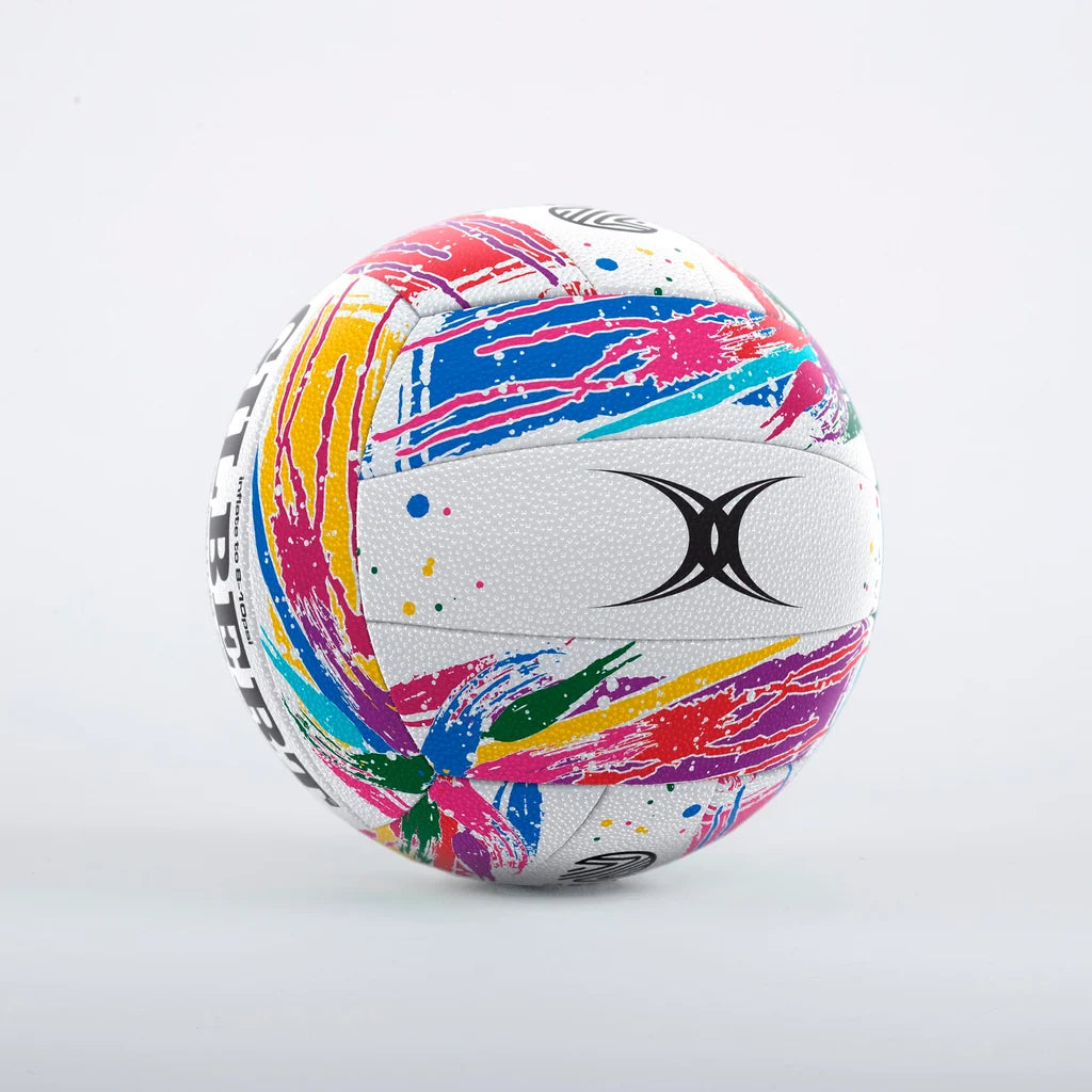 A white gilbert size 5 netball with a vibrant multicolor paint-splatter pattern set against a white background.