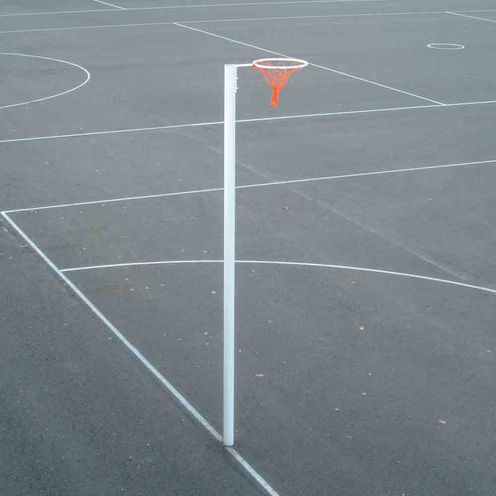 A freestanding white pole with an orange net and white hoop, set on a dark asphalt court with white painted lines.