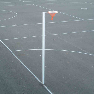 A freestanding white pole with an orange net and white hoop, set on a dark asphalt court with white painted lines.