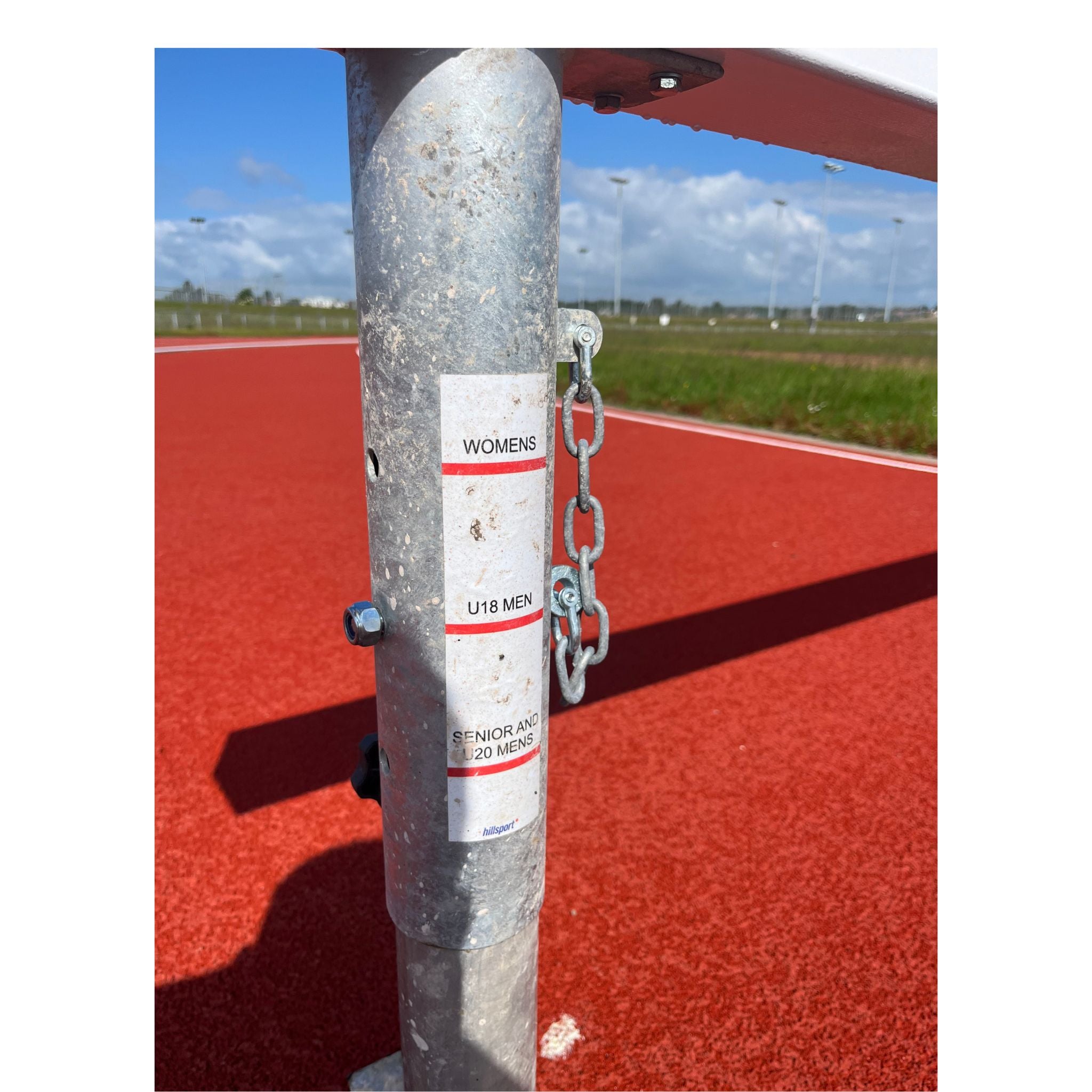 Metal leg of a steeplechase hurdle with a label indicating hurdle heights for women, U18 men and senior men.