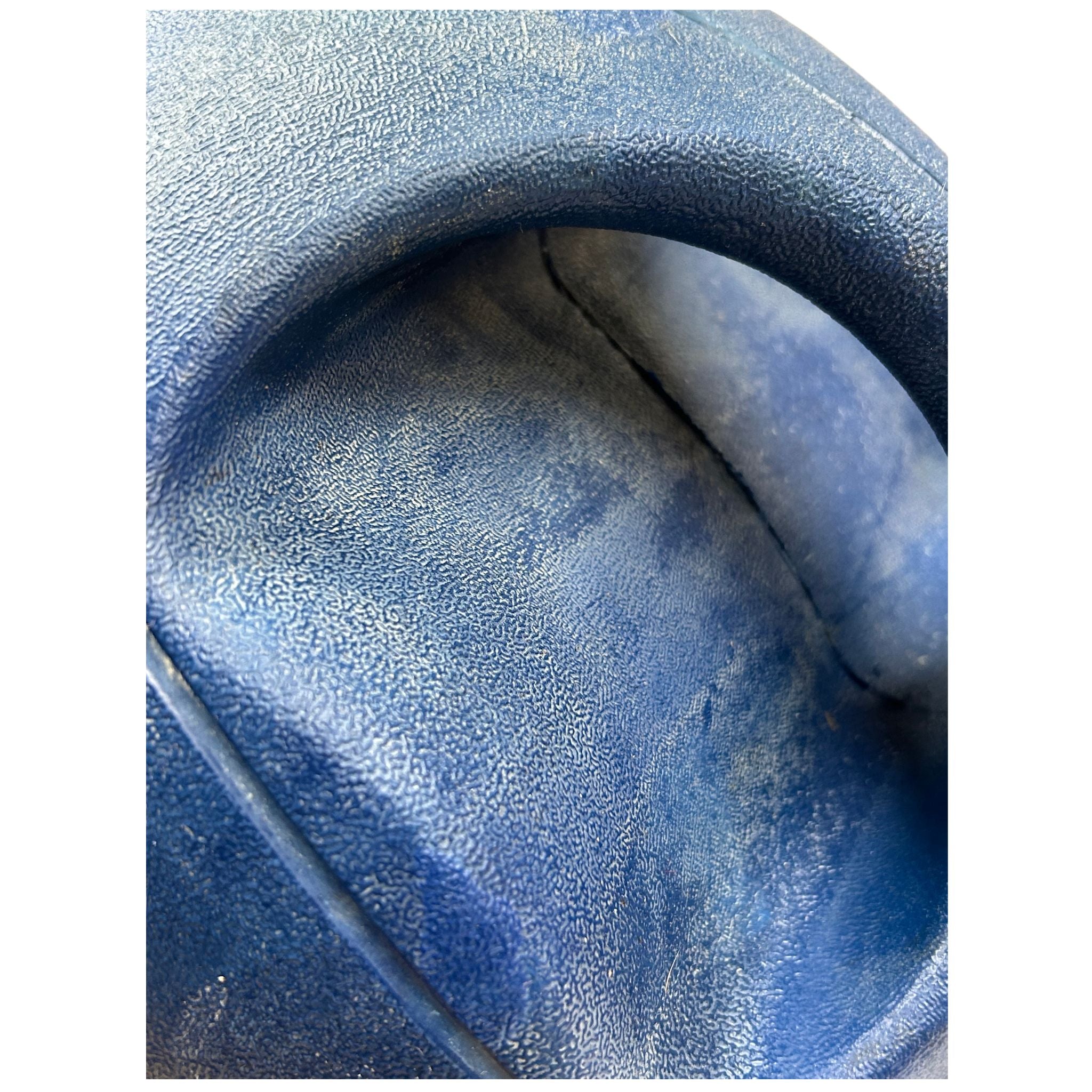 Close-up detail of a textured blue molded plastic or rubber surface with a curved recessed channel.